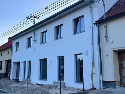 Rodinný dům s bílou fasádou a tmavou střechou