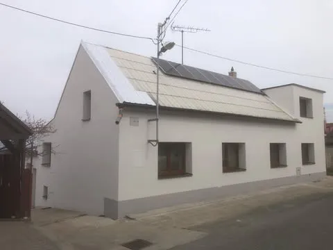 Dům se zateplenou fasádou a solárními panely na střeše